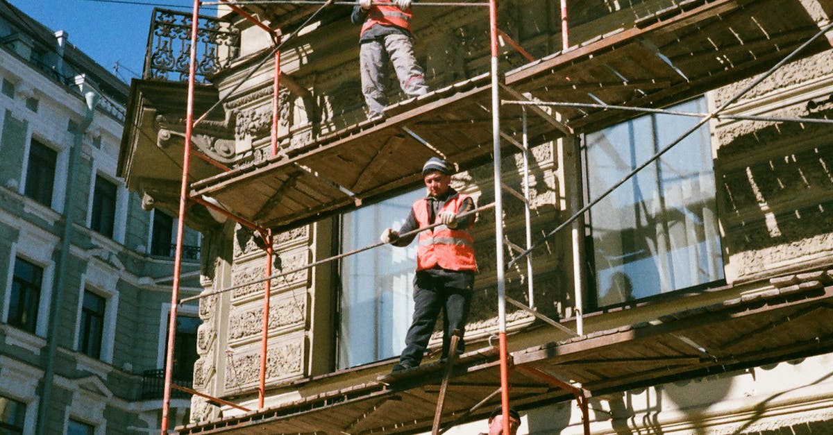 Construction workers on scaffolding renovating a building facade on a sunny day.